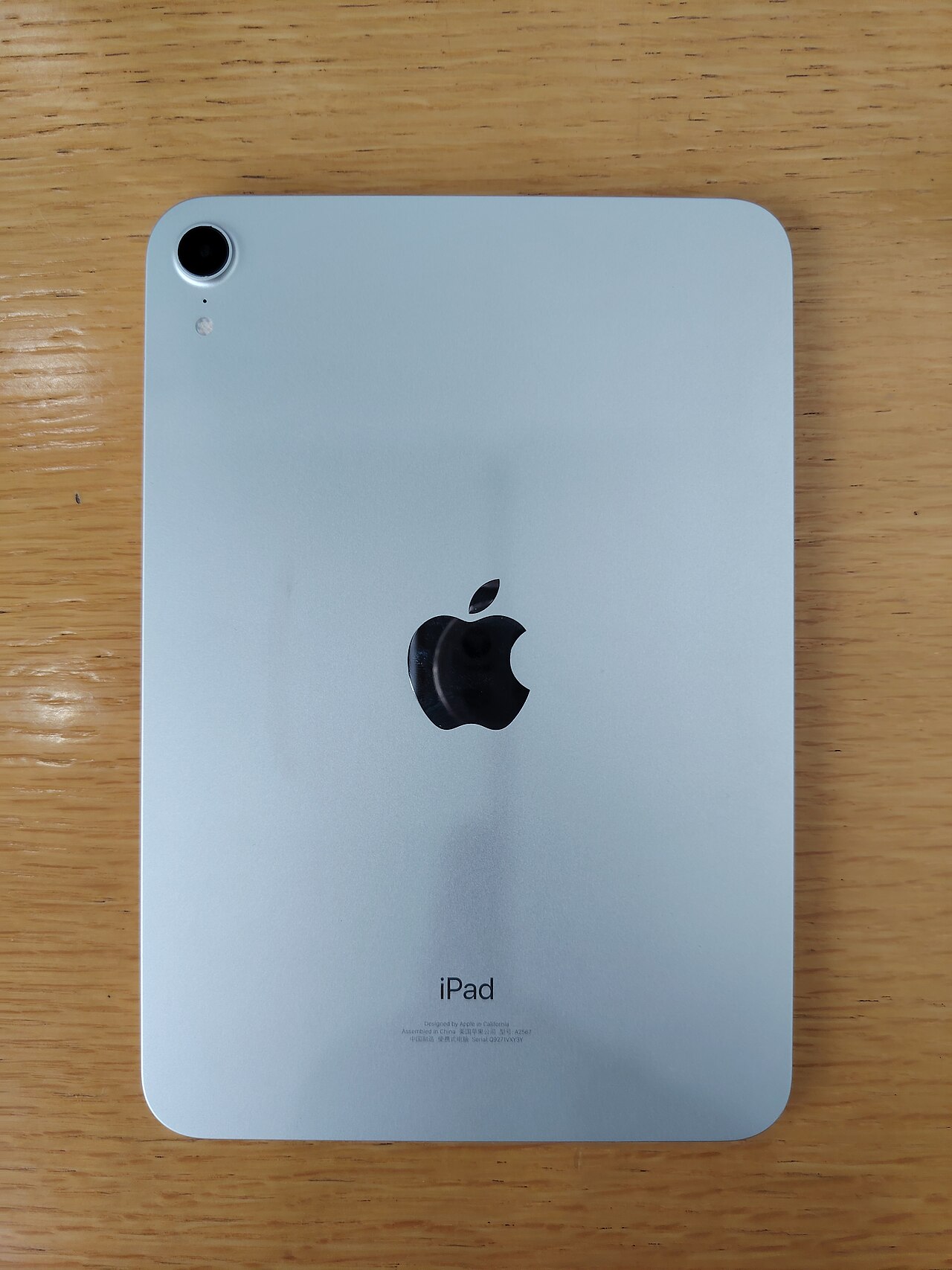 Back of an earlier sixth-generation iPad mini on a wooden table; not the new 2026 model