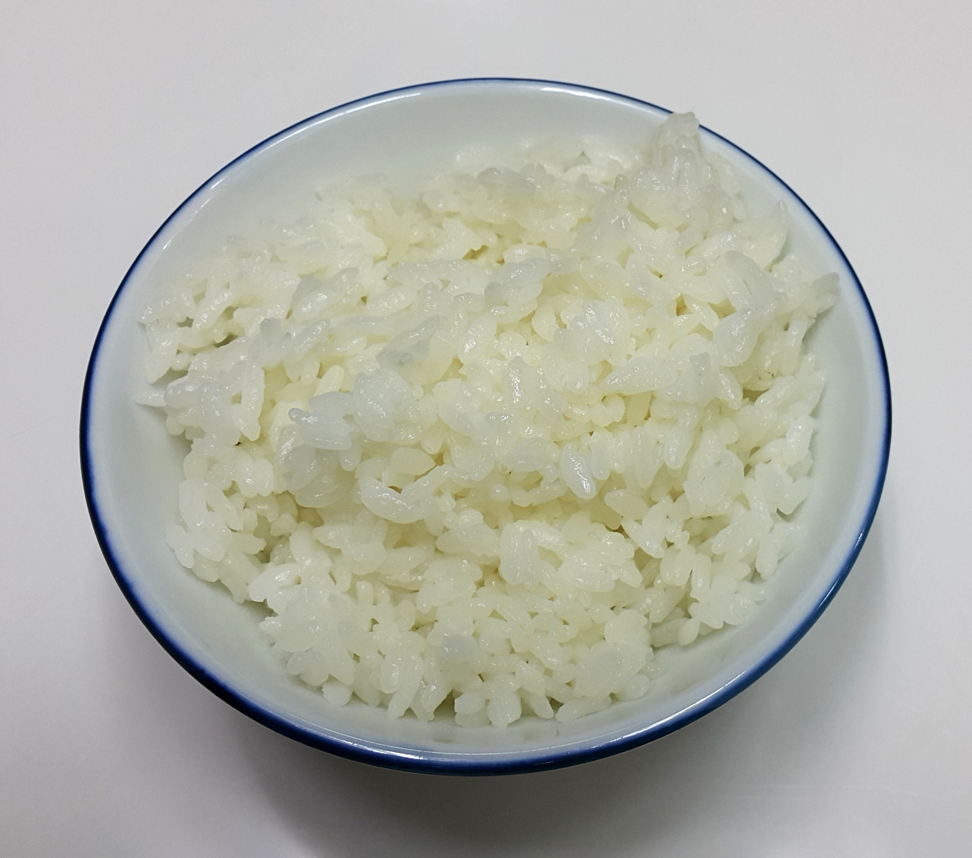 Plain cooked white rice in a white bowl with a blue rim; ingredient context, not miso soup rice or Nagatanien's packaged product